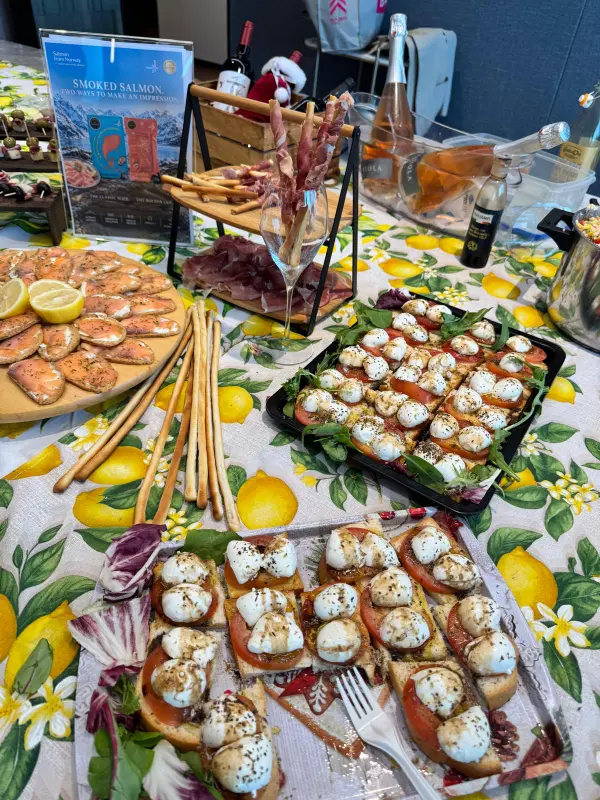 Tomato and mozzarella bruschetta, smoked salmon toasts, prosciutto-wrapped breadsticks and wine on a lemon-print tablecloth