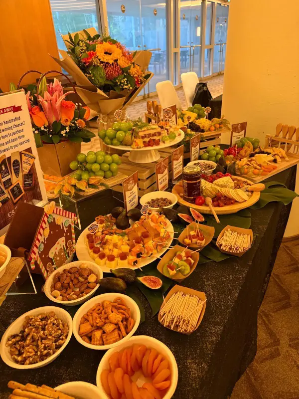 A cheese grazing table with cheese and fruit skewers, figs, grapes, nuts, dried apricots and flowers